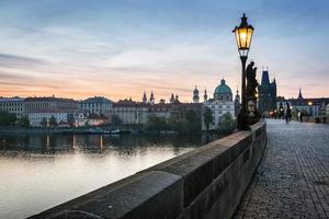 charles bridge ao nascer do sol, praga, república tcheca. estátuas dramáticas e torres medievais. foto