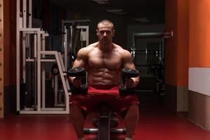 fisiculturista exercitar bíceps com halteres foto