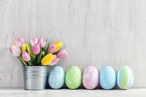 ovos de páscoa e um buquê de primavera de tulipas em uma mesa de madeira. foto