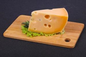 queijo maasdam no tabuleiro servido com folhas de salada foto