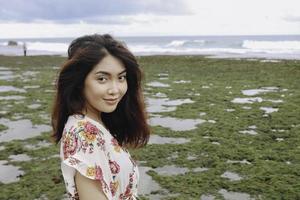 uma jovem asiática na praia está sorrindo para a câmera em gunungkidul, indonésia foto
