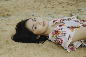 close-up vista superior de uma mulher sorridente deitada e relaxando na areia da praia foto