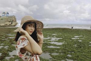 uma jovem asiática usando um chapéu de praia está relaxando na praia de céu azul em gunungkidul, indonésia foto