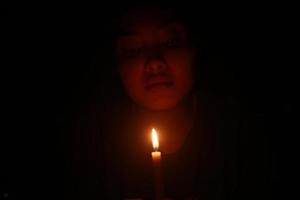 uma mulher asiática assustadora com vela na noite escura foto