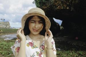 uma jovem garota asiática bonita usando um chapéu de sol está relaxando na praia de céu azul em gunungkidul, indonésia foto