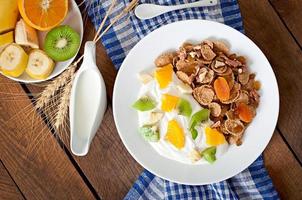 sobremesa saudável com muesli e frutas em um prato branco em cima da mesa foto