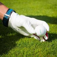 mão segure a bola de golfe com tee no curso, close-up