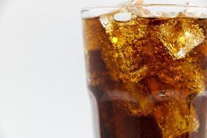 copo de cola com esmagado em um fundo branco gelo de cola em vidro e há gotas de água ao redor. bebida fresca preta fresca. foto