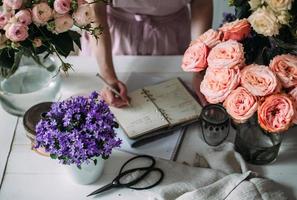 uma florista escreve em um caderno de artesanato em uma loja entre as flores. foto