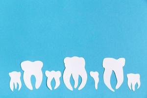 dentes cortados de papel em fundo azul foto