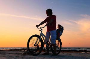 silhueta de pai e bebê, andar de bicicleta ao pôr do sol