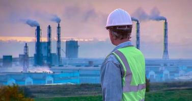 engenheiro sênior de vista traseira usando capacete e colete salva-vidas no fundo da fábrica foto