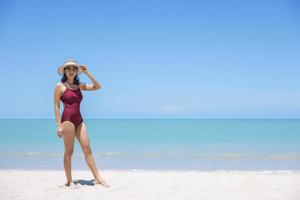 mulheres jovens de biquíni e chapéu de palha ficam na praia tropical, apreciando a vista do oceano da praia em um dia quente de verão. mar azul no fundo. khao lak, phang nga, tailândia. conceito de férias de verão foto