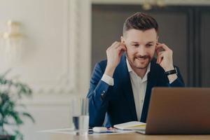 empresário bonito ajustando fones de ouvido durante a conferência web foto