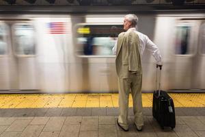 empresário sênior, esperando o trem na estação de metrô foto