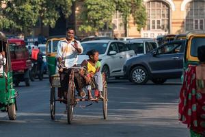 vadodara, índia, novembro de 2018 - motorista de riquixá indiano montando um ciclo riquexó na estrada foto