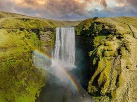 famosa cachoeira skogafoss com um arco-íris. cenário dramático da islândia durante o pôr do sol. foto