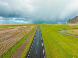 estrada sem fim para as montanhas nubladas e colinas da islândia durante o tempo nublado ensolarado. foto