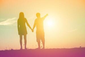 silhueta de um homem e uma mulher de mãos dadas, caminhando juntos. foto