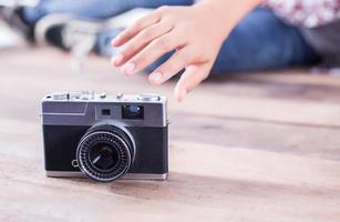 mulher jovem fotógrafo hipster tirando foto e olhe para a câmera sentada no chão de madeira.