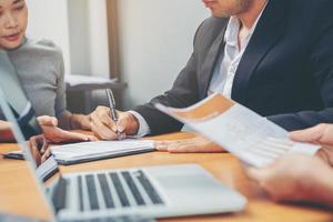 empresário coloca assinatura no contrato na reunião de negócios e passa dinheiro após negociações com parceiros de negócios. foco selecionado foto