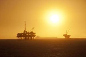 plataformas de petróleo ao pôr do sol.