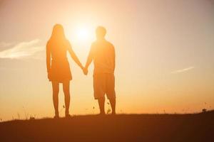 silhueta de um homem e uma mulher de mãos dadas, caminhando juntos. foto