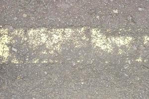 superfície da estrada velha tem linhas amarelas descascando. foto