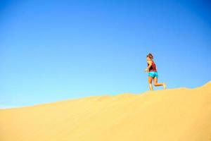 mulher correndo nas dunas do deserto de areia foto