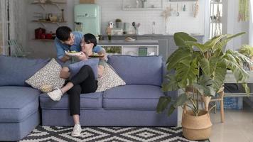 jovem casal gay sorridente com comida saudável na sala de estar em casa, lgbtq e conceito de diversidade. foto