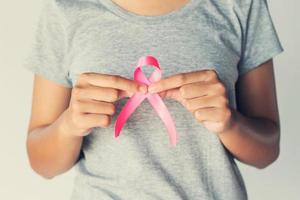 mão de mulher segurando a conscientização do câncer de mama de fita rosa. conceito de saúde e medicina foto