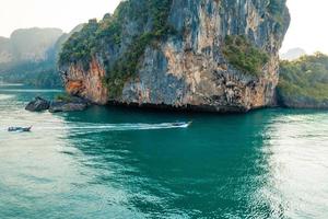 vista para o mar e ilhas rochosas com um barco de cauda longa. foto