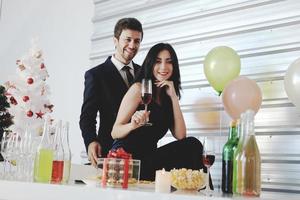 doce casal adora sorrir e passar romântico bebendo vinho na época do natal e comemorando a véspera de ano novo, dia dos namorados com balão colorido e caixas de presente na despensa foto