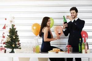 doce casal adora sorrir e passar romântico bebendo vinho na época do natal e comemorando a véspera de ano novo, dia dos namorados com balão colorido e caixas de presente na despensa foto