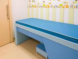 a pequena cama de exame vazia na sala de exame infantil. foto