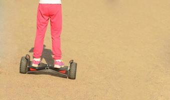 menina está dirigindo na scooter elétrica de auto-equilíbrio em day.walking ensolarado em segway na areia. foto