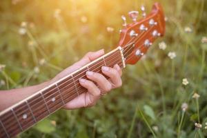 mulher jovem hippie tocando violão para relaxar em suas férias, divirta-se com ar natural e fresco. foto