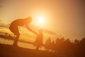 silhuetas de mãe e filha caminhando ao pôr do sol foto