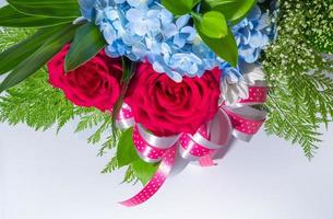 grandes rosas vermelhas e pequenas flores azuis frágeis inserem folhas no lindo buquê de flores foto
