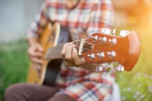 mulher jovem hippie tocando violão para relaxar em suas férias, divirta-se com ar natural e fresco. foto