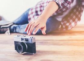 mulher jovem fotógrafo hipster tirando foto e olhe para a câmera sentada no chão de madeira.