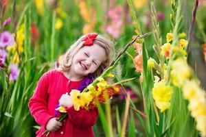 criança colhendo flores frescas tipo gladíolo
