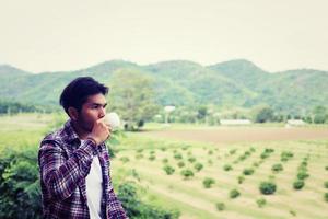 homem barbudo hipster bonito com café da manhã andando no parque. foto