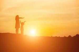 mãe incentivou a filha a sair das sombras ao pôr do sol. foto