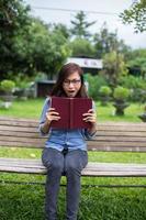 uma mulher sentada no jardim lendo um livro. foto