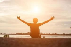 esportista de sucesso, levantando os braços no céu dourado, iluminação por do sol, verão, após a corrida cruzada. atleta masculino de fitness com os braços para cima comemorando objetivos após o esporte se exercitando e malhando ao ar livre. foto