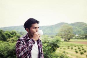 homem barbudo hipster bonito com café da manhã andando no parque. foto