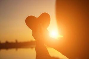 mãos formando um coração com silhueta por do sol foto