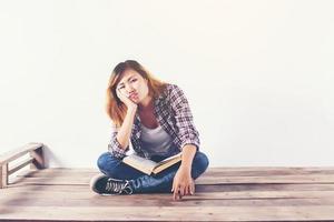 mulher jovem hippie segurando livros e apontando para cima no fundo branco isolado. foto