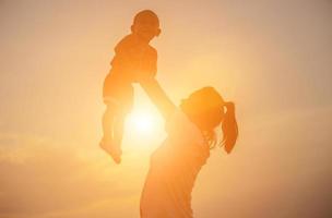 silhuetas de mãe e filha caminhando ao pôr do sol foto